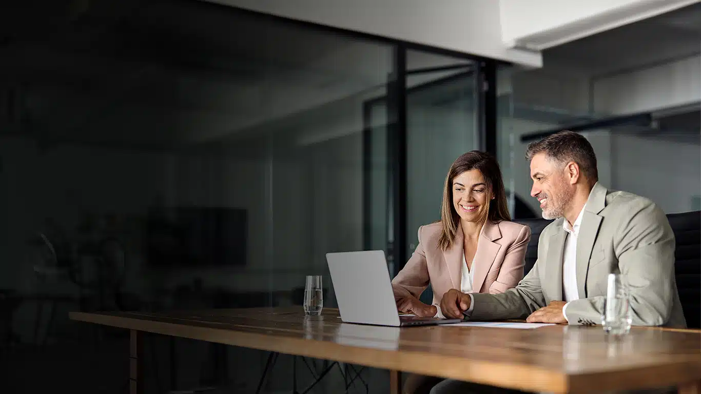 Two business professionals sharing a laptop to view a quality management system review